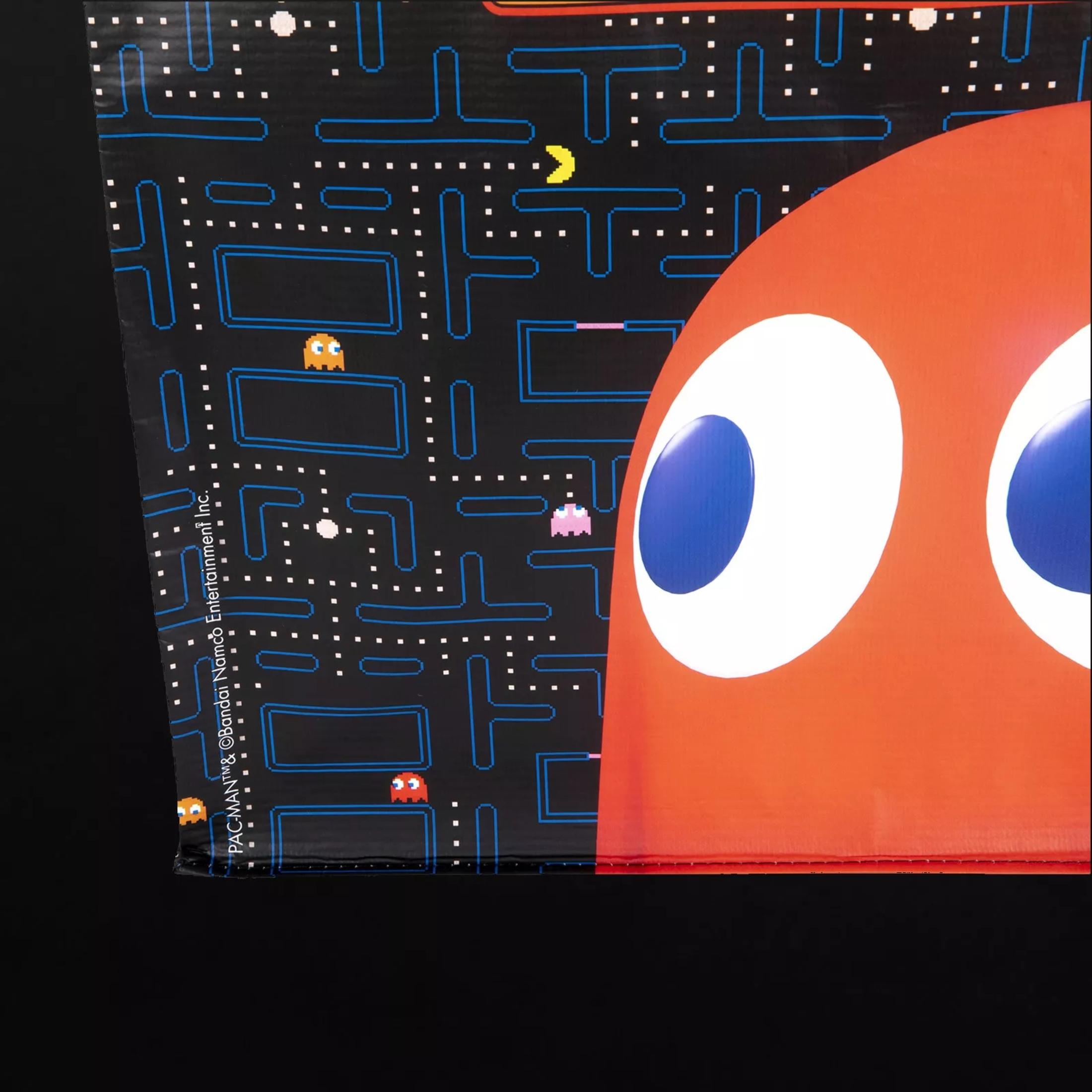 Eine Pac-Man-Einkaufstasche auf einer schwarzen Oberfläche. Die Tasche hat Pac-Man auf der Vorderseite.