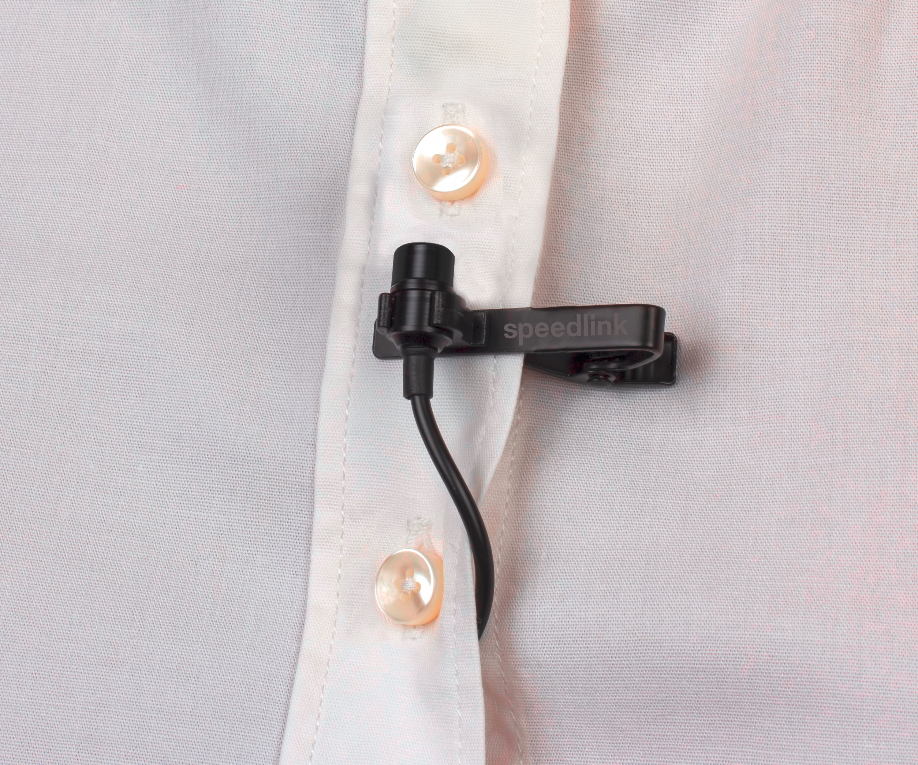 Un microfono Speedlink agganciato a una camicia bianca con tre bottoni visibili.