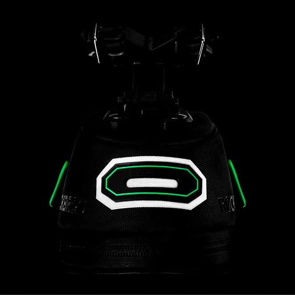 Zbliżenie czarnej torby podsiodłowej. Widoczne zielone akcenty i świecące logo.