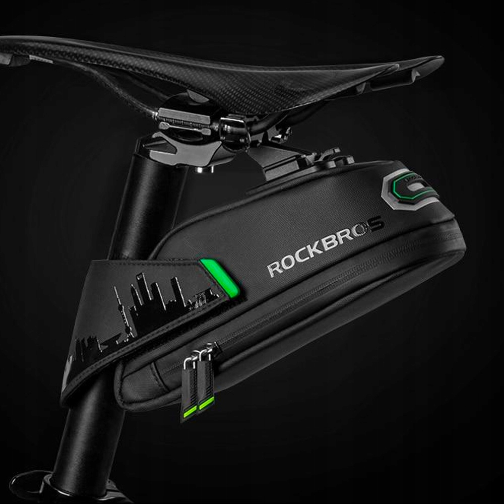 Czarna torba podsiodłowa przymocowana do sztycy. Widoczna panorama miasta i zielone akcenty.