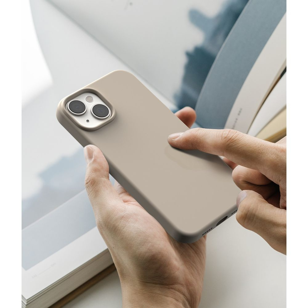 Dłonie trzymające telefon w etui, otwierające książkę.