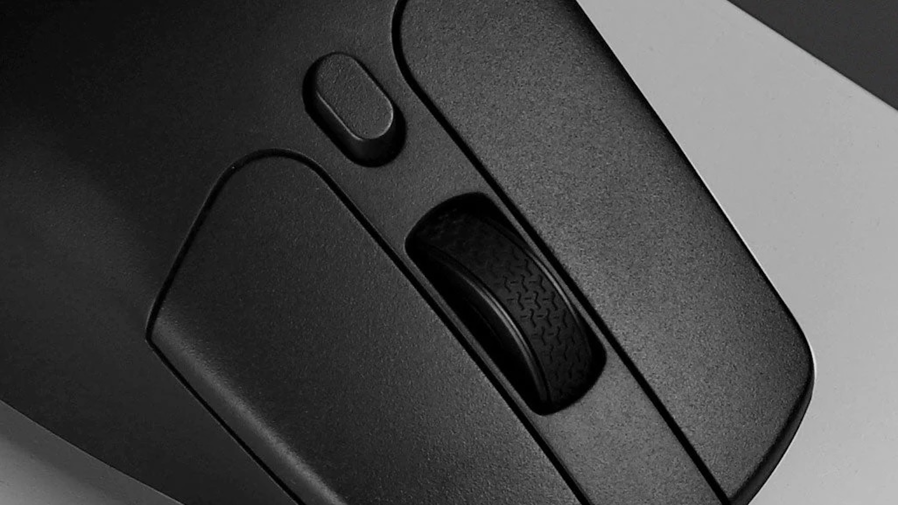 Zbliżenie czarnej myszy komputerowej, pokazujące kółko przewijania i przyciski.