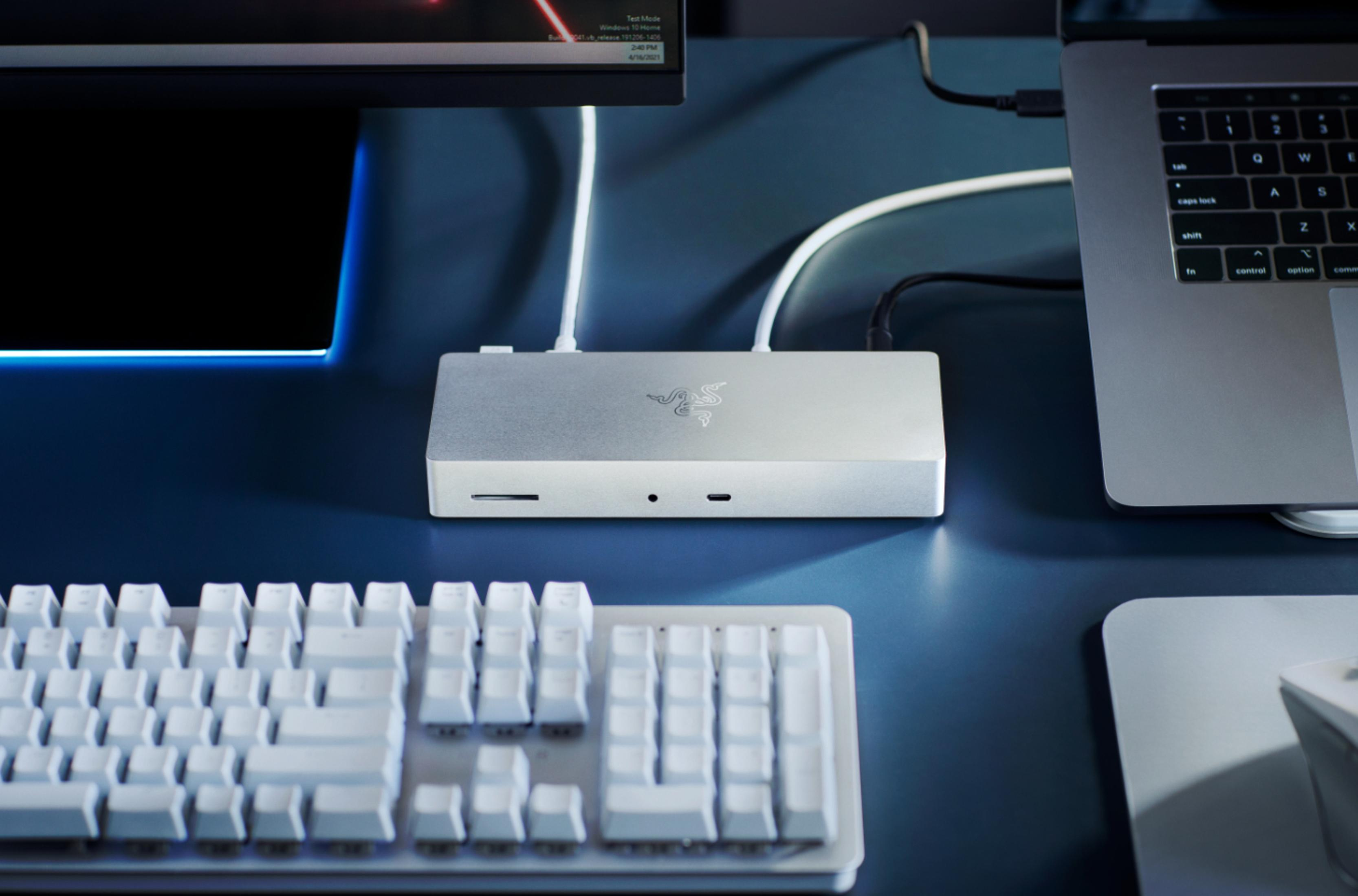 Ein Schreibtisch-Setup mit Monitor, Razer-Dockingstation, Tastatur und Laptop. Der Monitor ist angeschlossen.