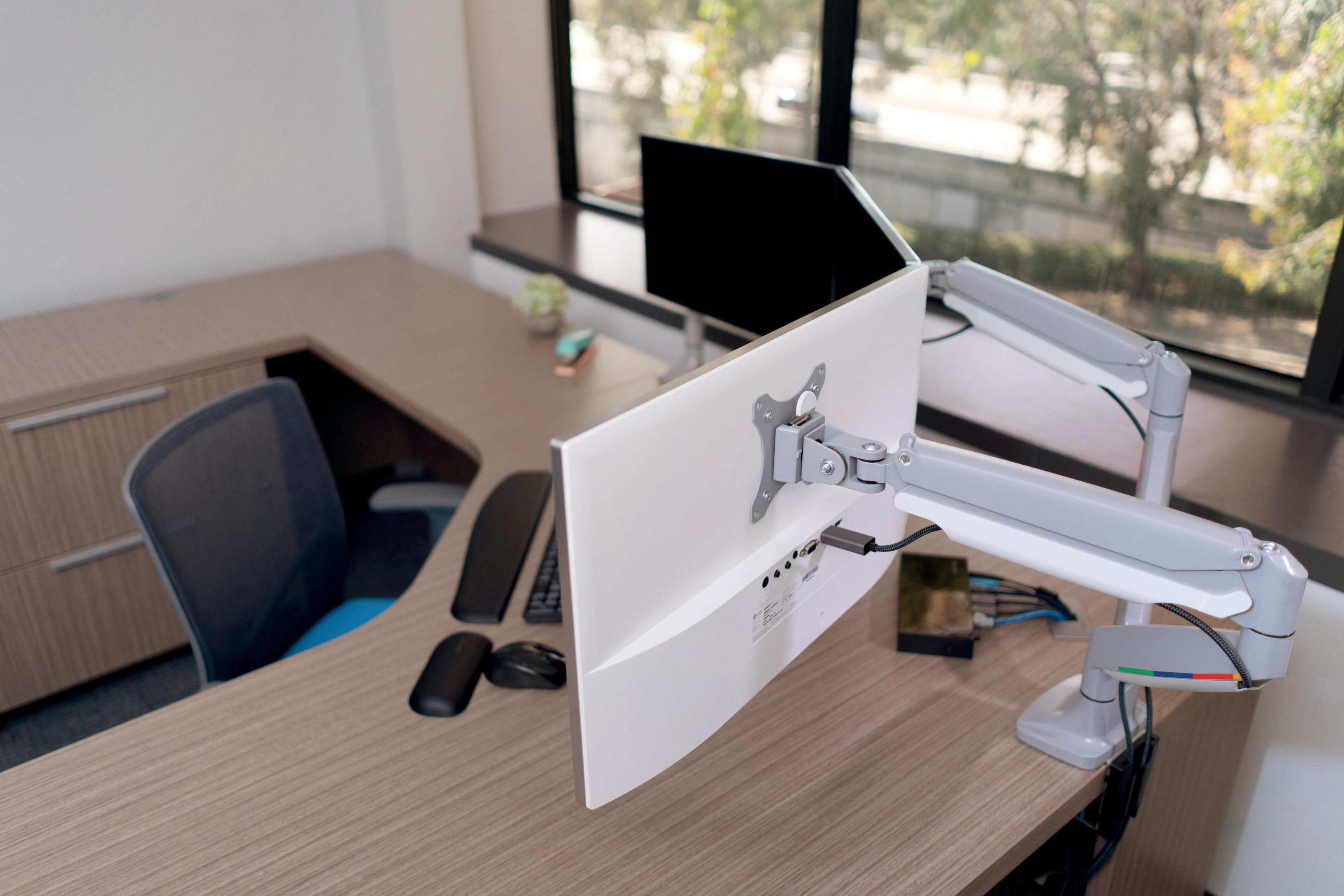 Ein Bürotisch mit zwei Monitoren, die von Monitorarmen getragen werden.