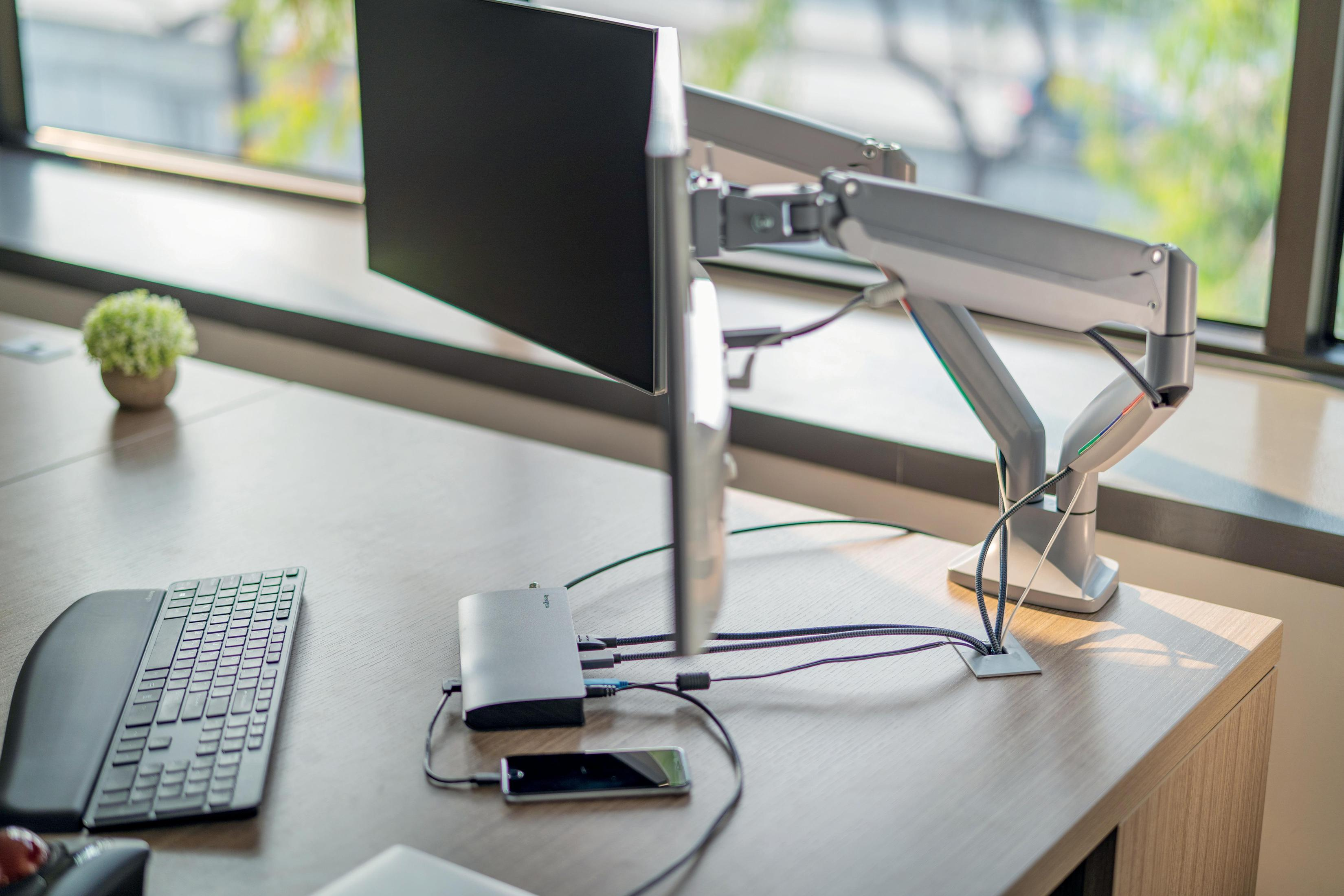 Ein Schreibtisch mit Monitor, Tastatur und anderen technischen Komponenten.