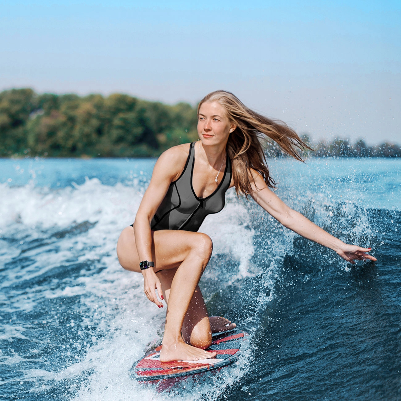 Frau auf einem Surfbrett im Wasser. Sie trägt einen schwarzen Badeanzug.