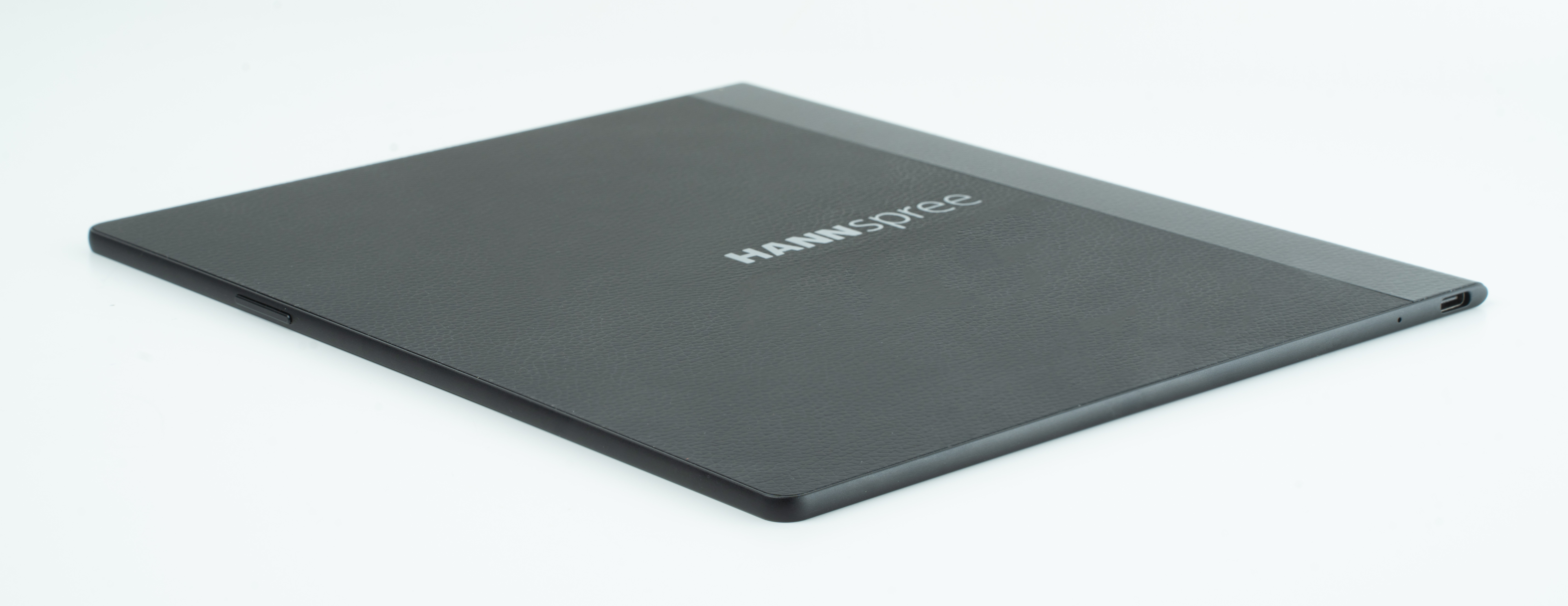 Un tablet nero con il nome 'HANNSspree' sulla cover, visto da un'angolazione, su una superficie bianca.