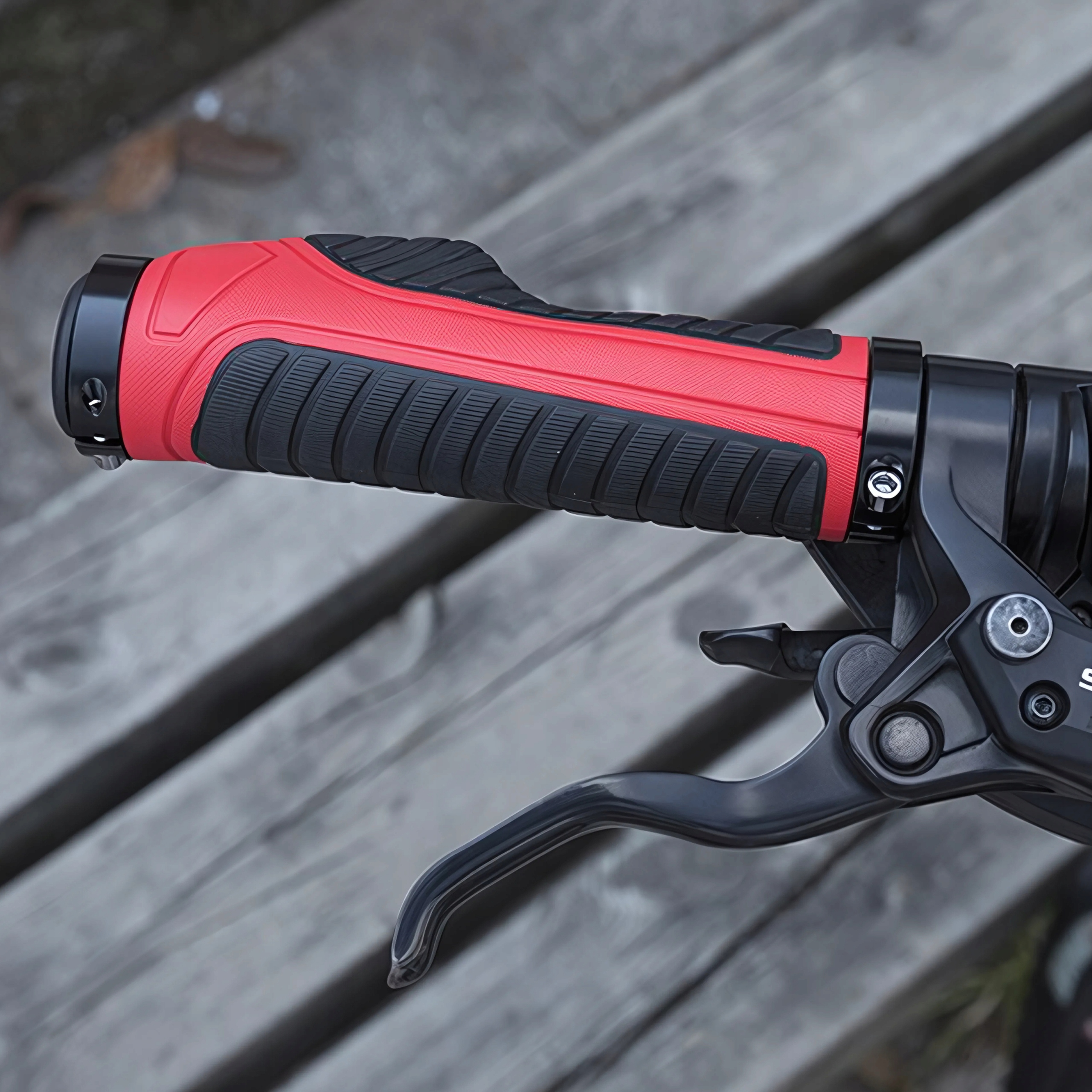 Czerwono-czarny uchwyt rowerowy na kierownicy z dźwignią hamulca na drewnianej powierzchni.