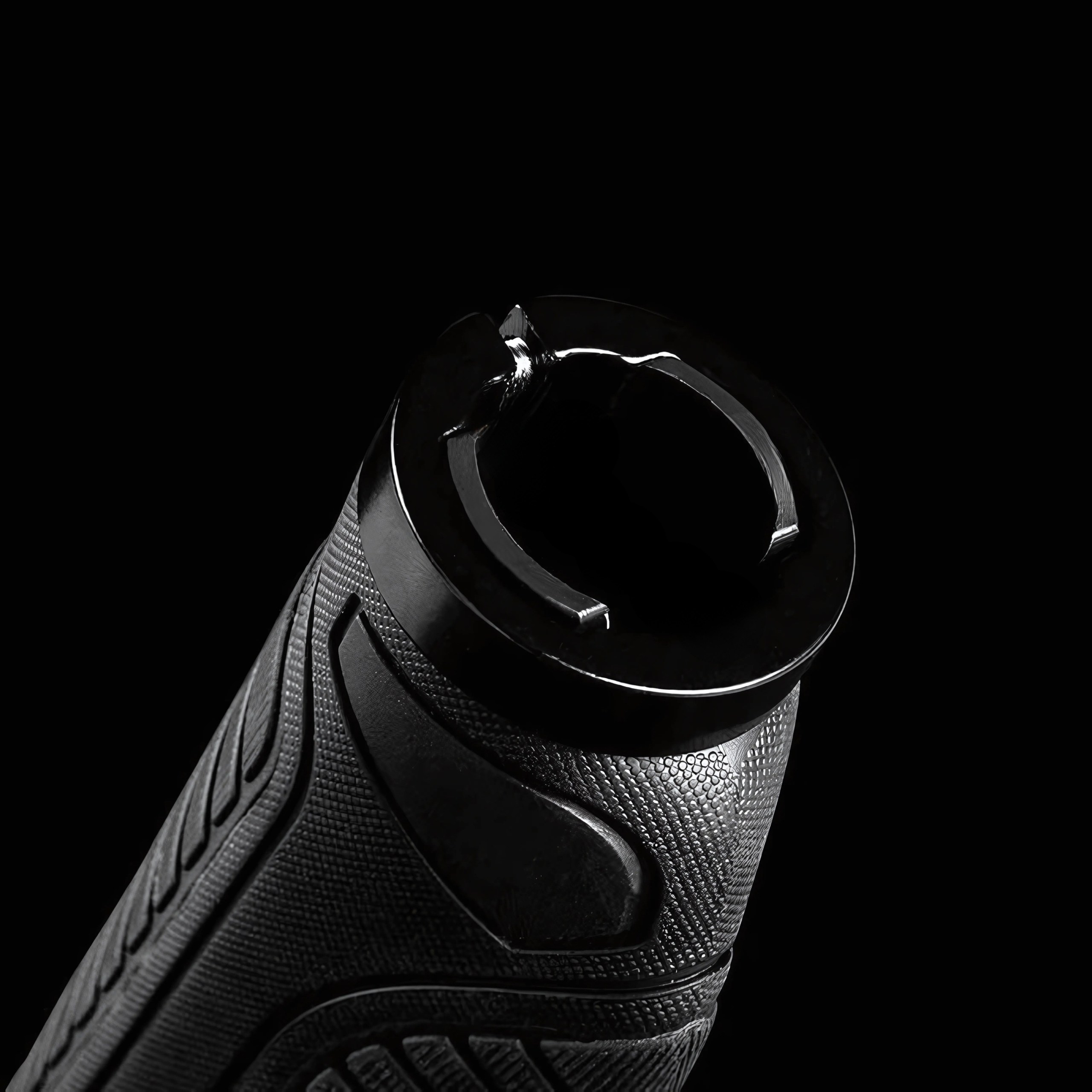 Zbliżenie czarnego końca uchwytu kierownicy roweru z pierścieniem na czarnym tle.