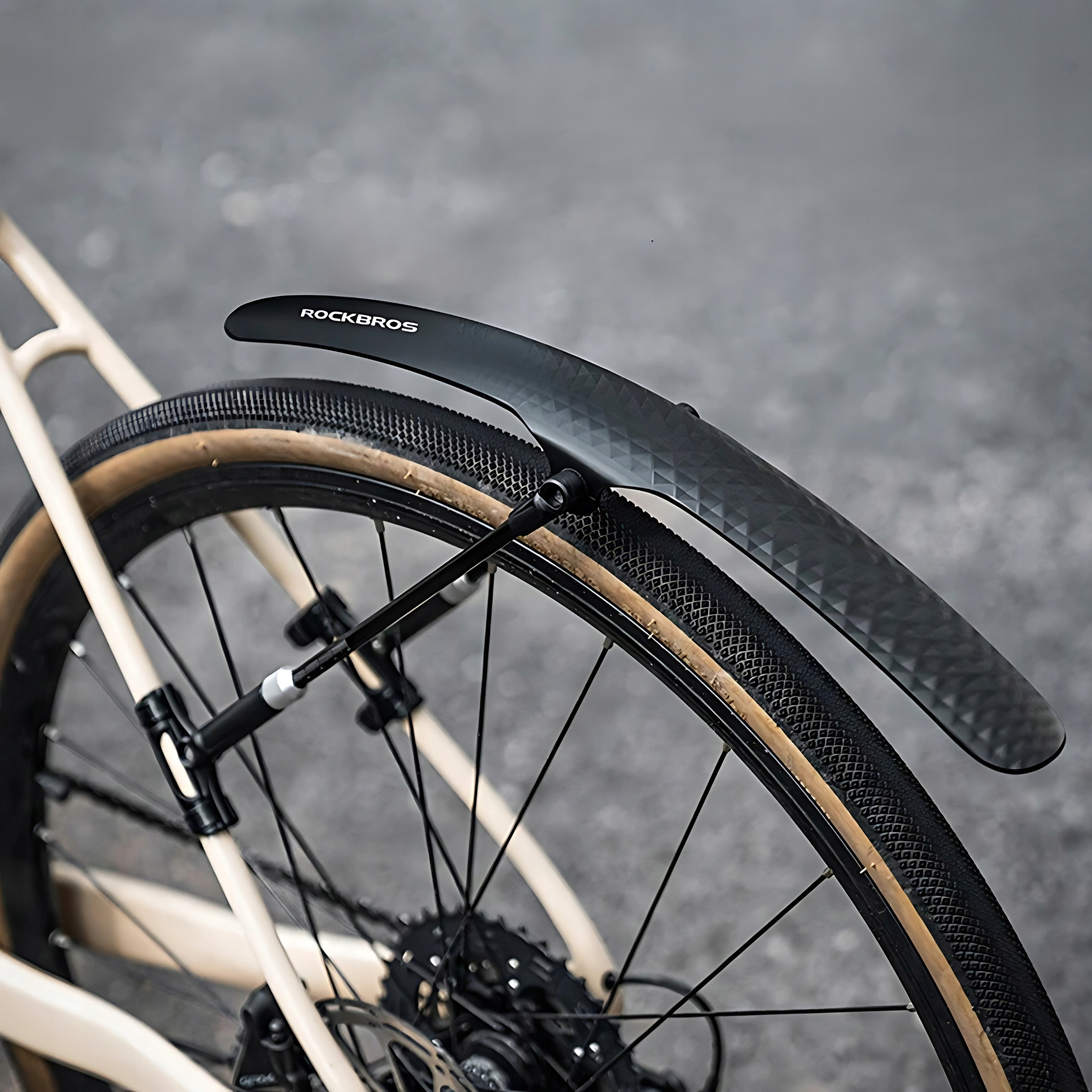 Zbliżenie czarnego błotnika ze słowem ROCKBROS na górze, przymocowanego do brązowej opony.