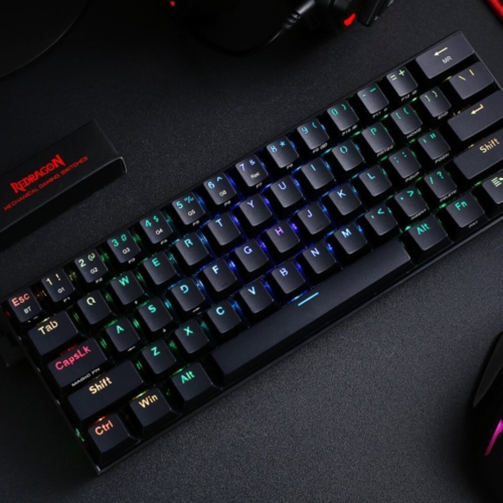 Teclado mecánico negro con teclas retroiluminadas RGB en superficie oscura, logo Redragon.