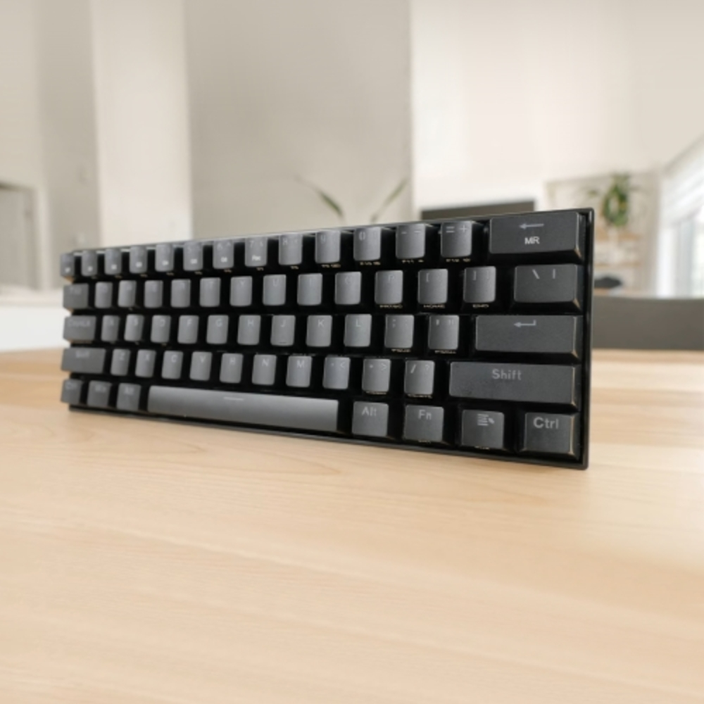 Teclado negro sobre una mesa de madera con fondo borroso.