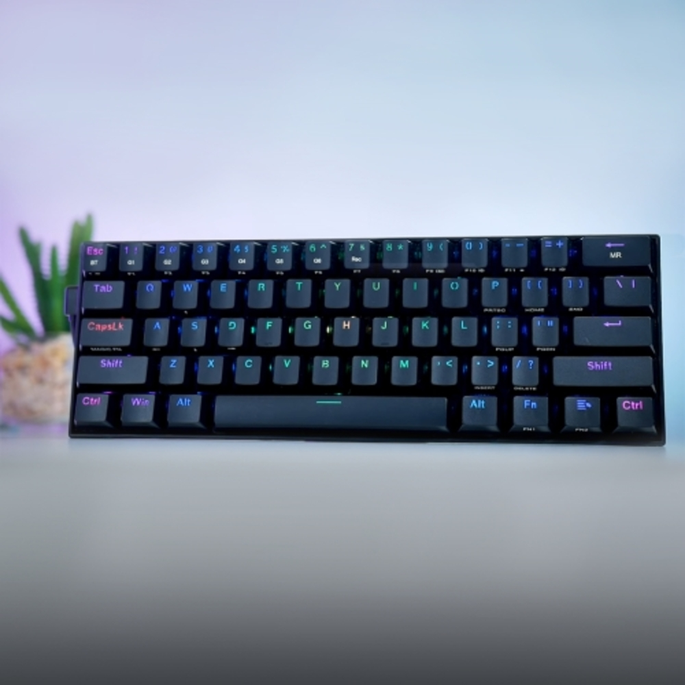 Teclado negro con teclas RGB, una planta y fondo morado y blanco.