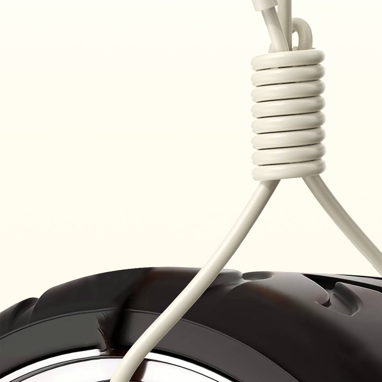 Biały kabel ładujący zwisa z góry, z przedmiotem przypominającym oponę na dole.