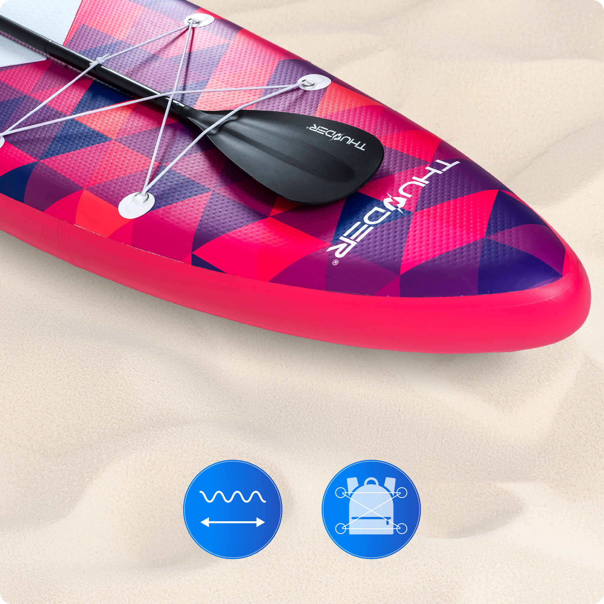 Zbliżenie deski SUP z różowym, fioletowym i czerwonym geometrycznym wzorem na piaszczystej plaży.