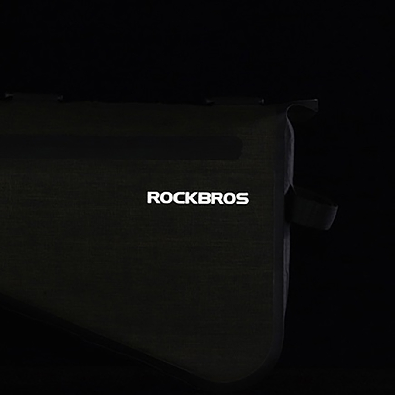 Zbliżenie szarej torby na ramę roweru z podświetlonym logo Rockbros, w ciemności.