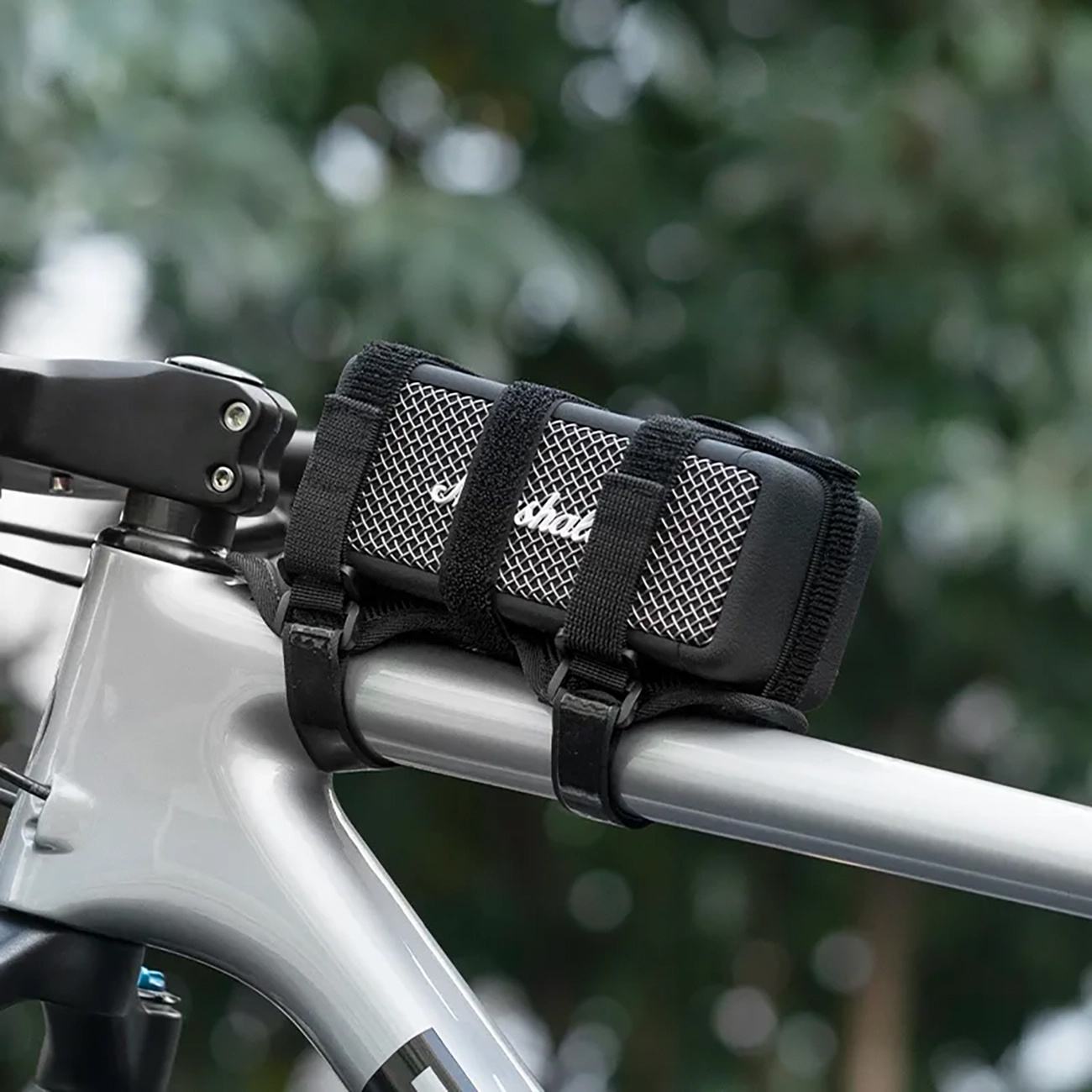 Czarny głośnik zamontowany na kierownicy roweru za pomocą dwóch pasków.