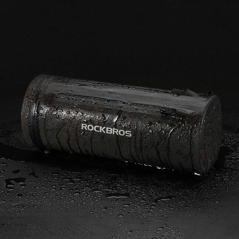 Czarna cylindryczna torba z napisem 'ROCKBROS' w kolorze białym. Krople wody na powierzchni, czarne tło.