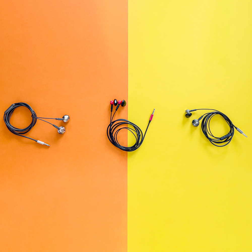 Słuchawki ułożone na podzielonym kolorystycznie tle pomarańczowym i żółtym.