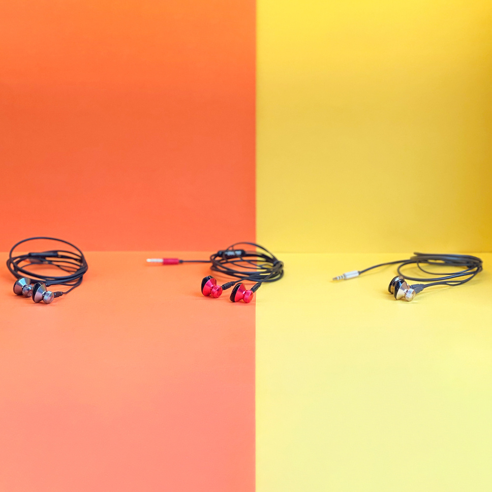 Słuchawki na podzielonym kolorystycznie tle pomarańczowym i żółtym. Układ jest symetryczny.