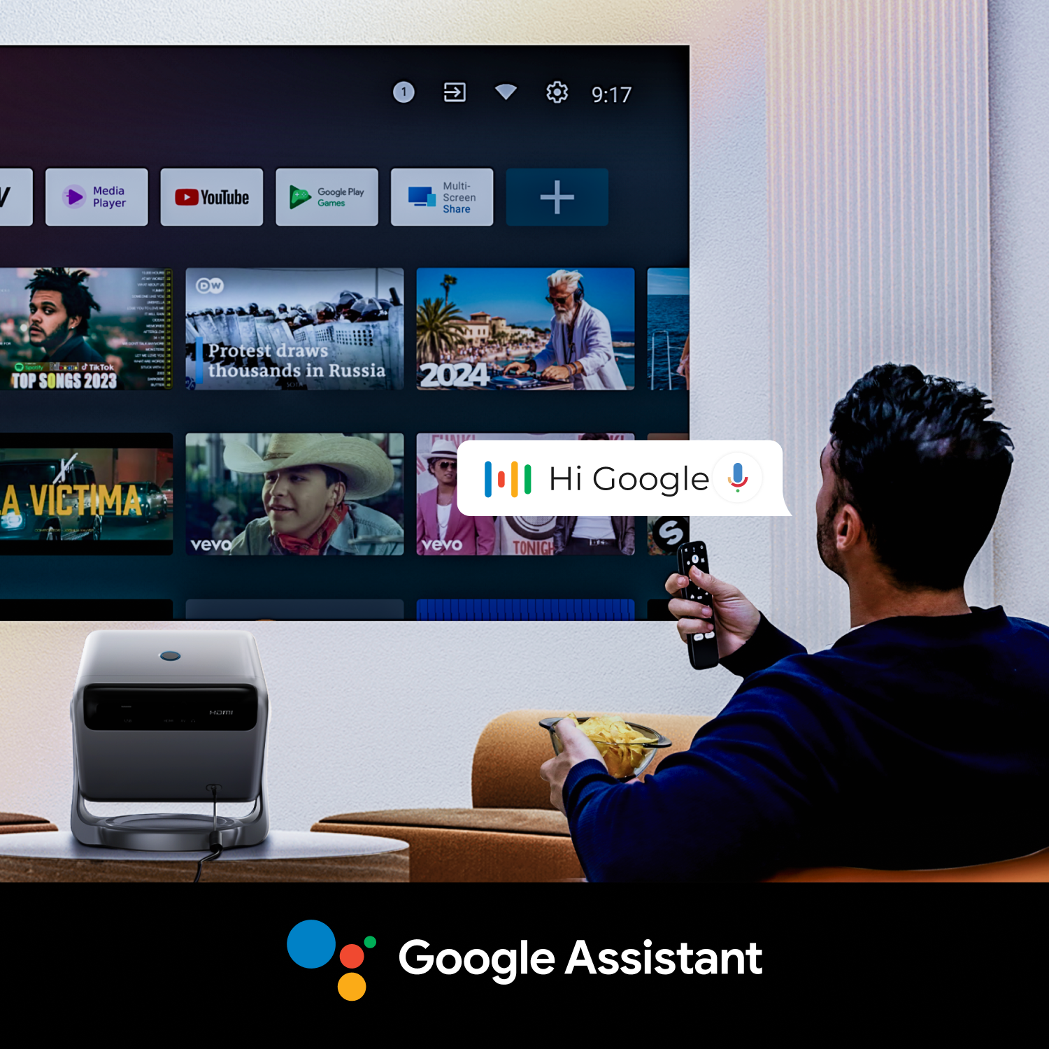 Mężczyzna używający Asystenta Google na telewizorze z projektorem, trzymając pilota.