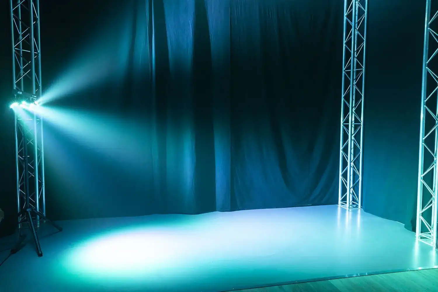 Escenario con luces azules. Hay una cortina oscura en el fondo.