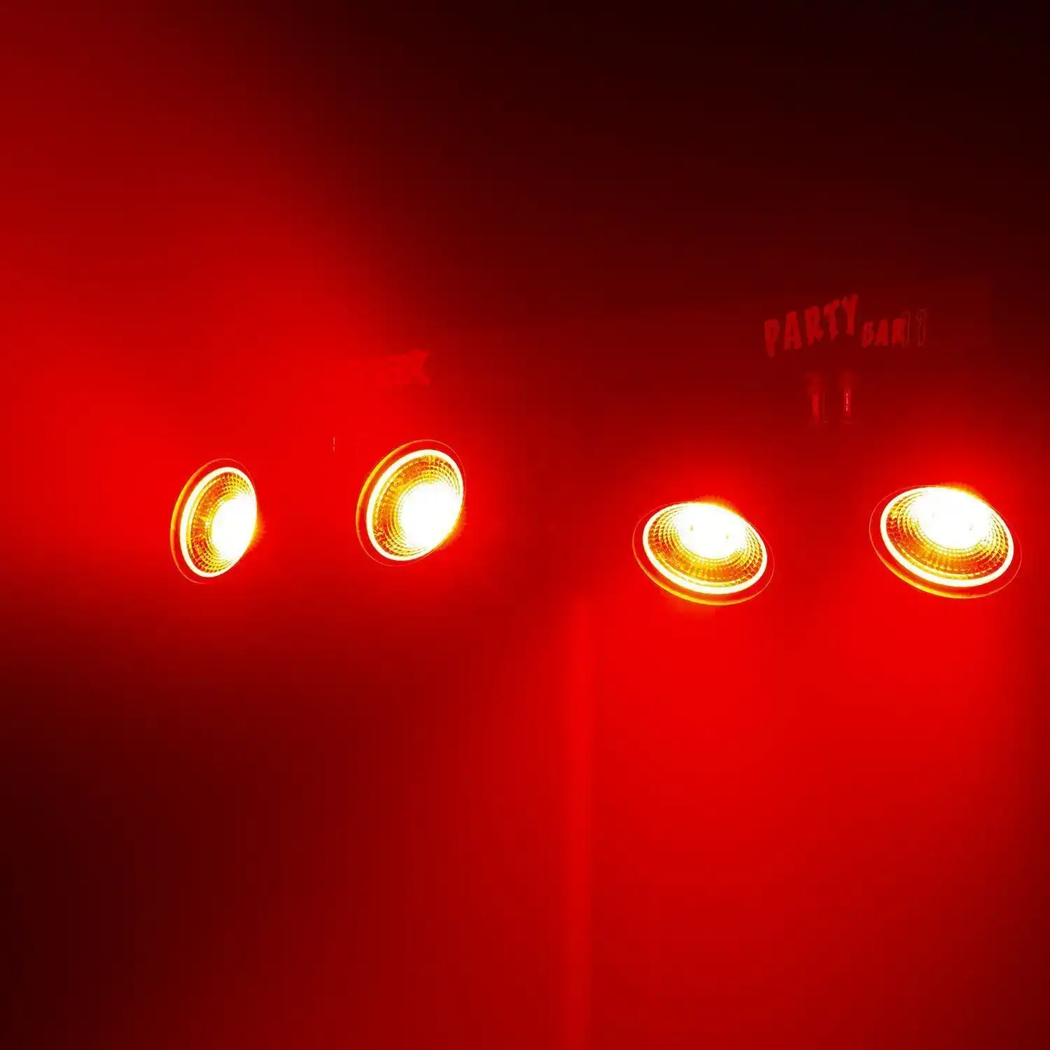Un fondo rojo oscuro con cuatro luces que emiten luz amarilla. Las luces están etiquetadas como 'PARTY BAR 1'.