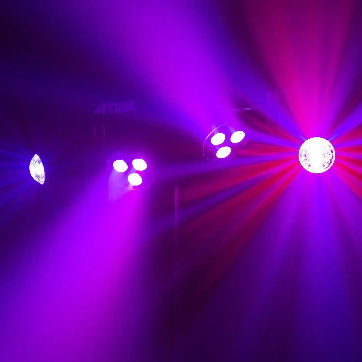 Luces de escenario creando haces de luz morados y rojos. Algunas luces en el fondo.
