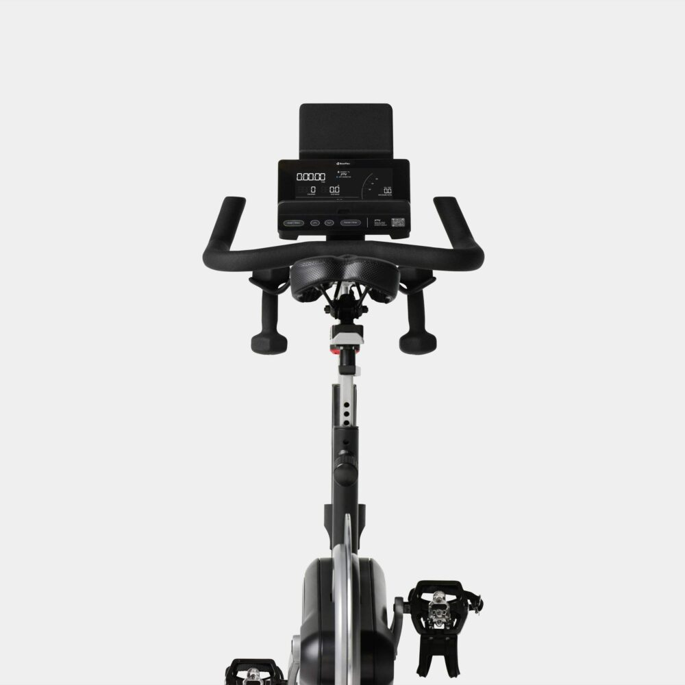 Primer plano de la pantalla digital de una bicicleta estática con manillar y asiento.