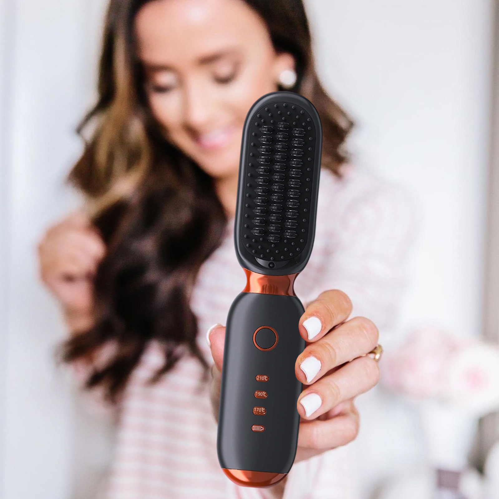 Frau, die eine schwarz-orange Haarglättungsbürste hält. Sie lächelt mit langen, welligen Haaren.
