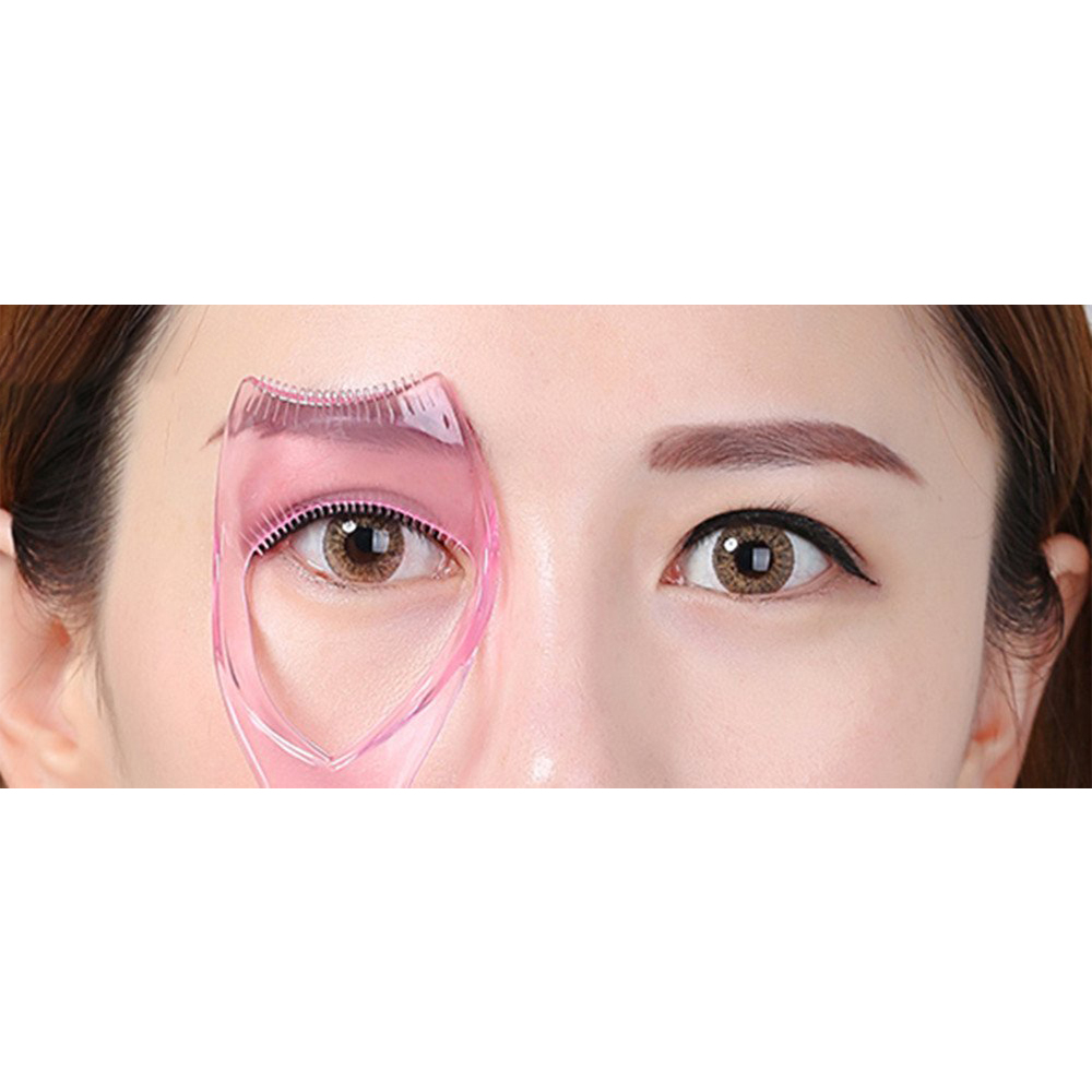 Das Auge einer Frau wird von einem rosa Wimpernwerkzeug umrahmt. Das Werkzeug wird über dem Auge verwendet, auf weißem Hintergrund.