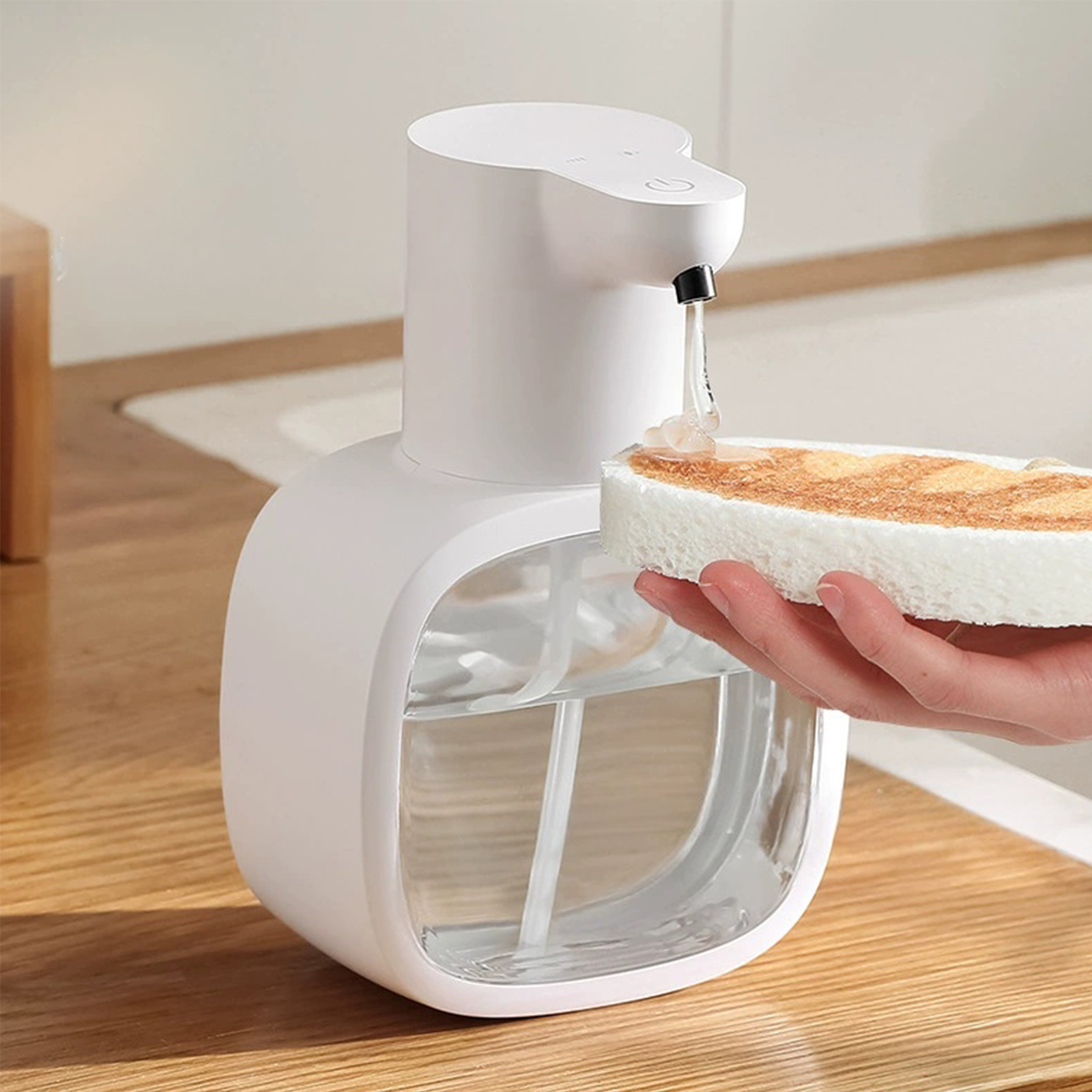 Ein weißer, automatischer Seifenspender, der Seife auf einen Schwamm abgibt. Der Spender hat ein klares Seifenreservoir.