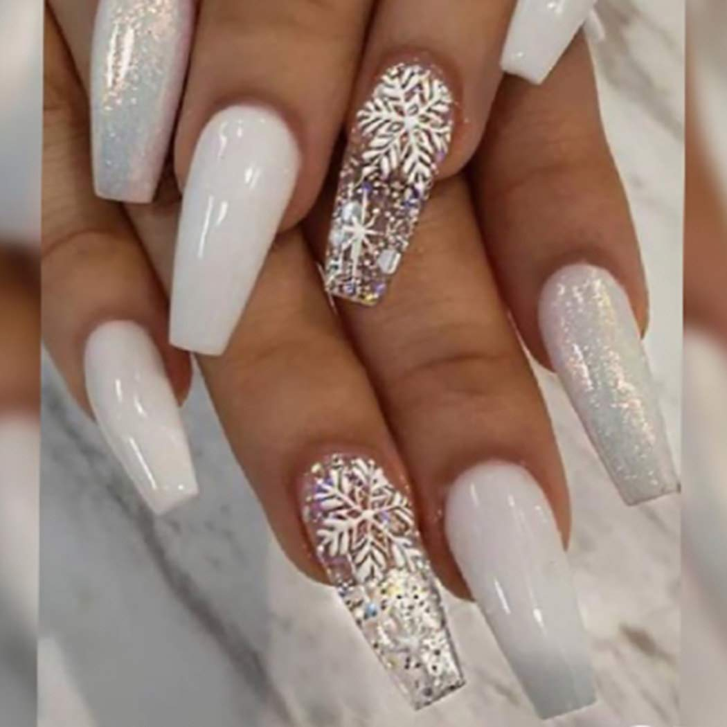 Manikürte Nägel mit weißem Nagellack und Schneeflocken- und Glitzer-Designs. Die Nägel sind lang, Sarg-förmig.