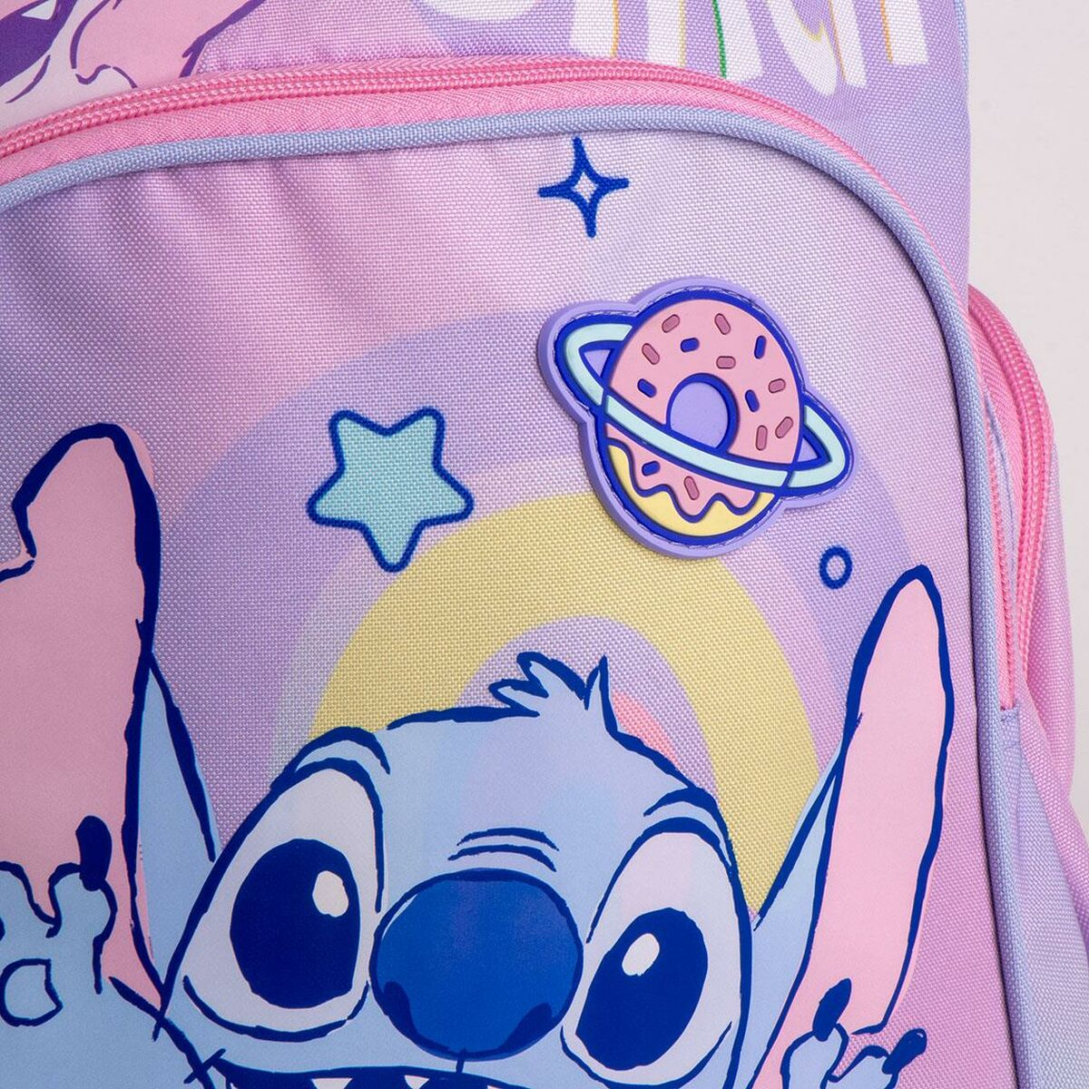 Nahaufnahme eines Rucksacks mit Stitch, einem planetenförmigen Donut, Sternen und einem Regenbogen.