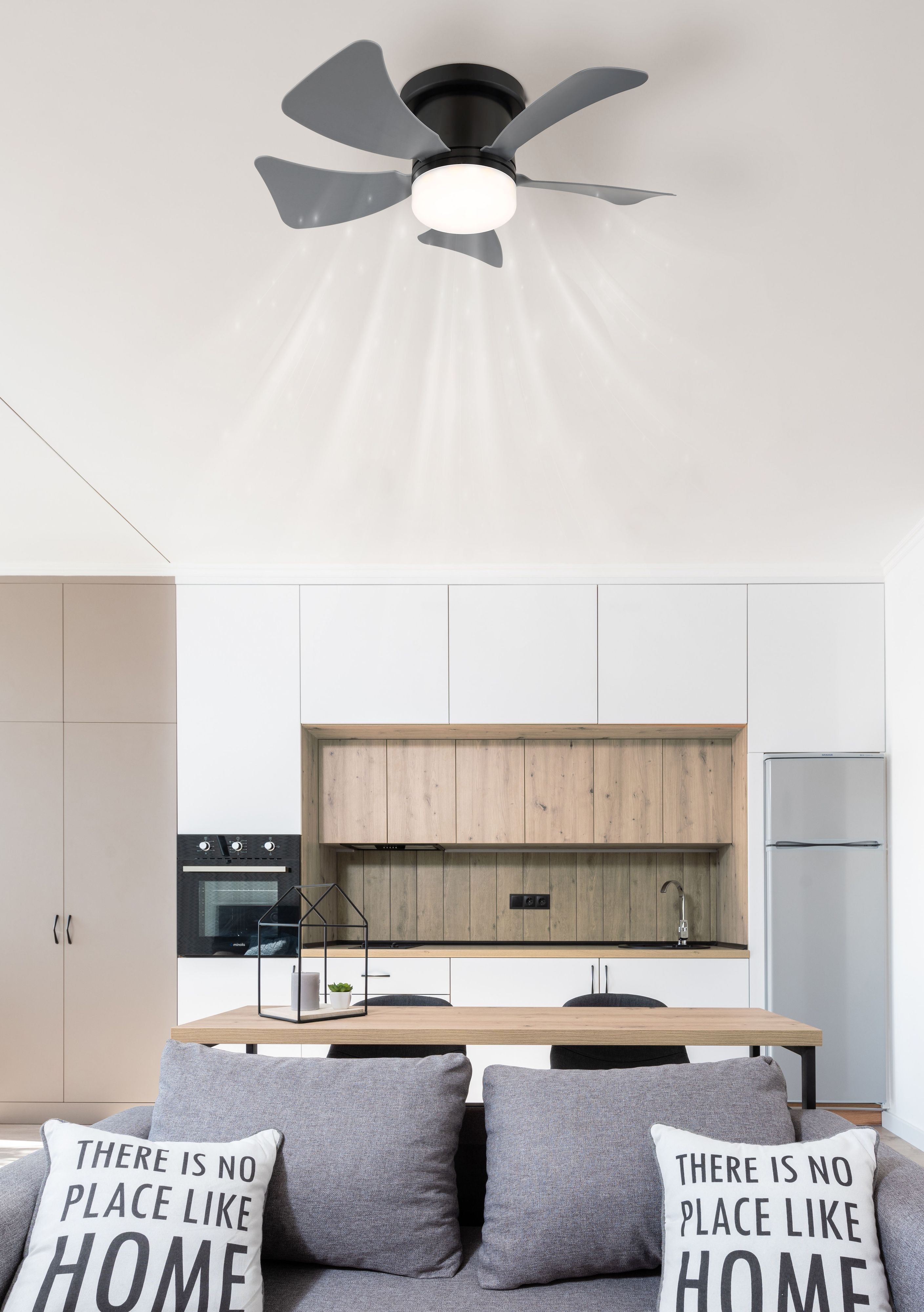Moderne Küche mit Deckenventilator. Der Ventilator ist schwarz und hat graue Flügel. Darunter ist ein Esstisch mit Kissen.