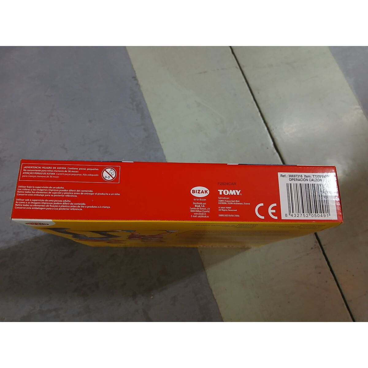 La parte inferior de una caja, con texto en varios idiomas. Tiene un código de barras y la marca CE.