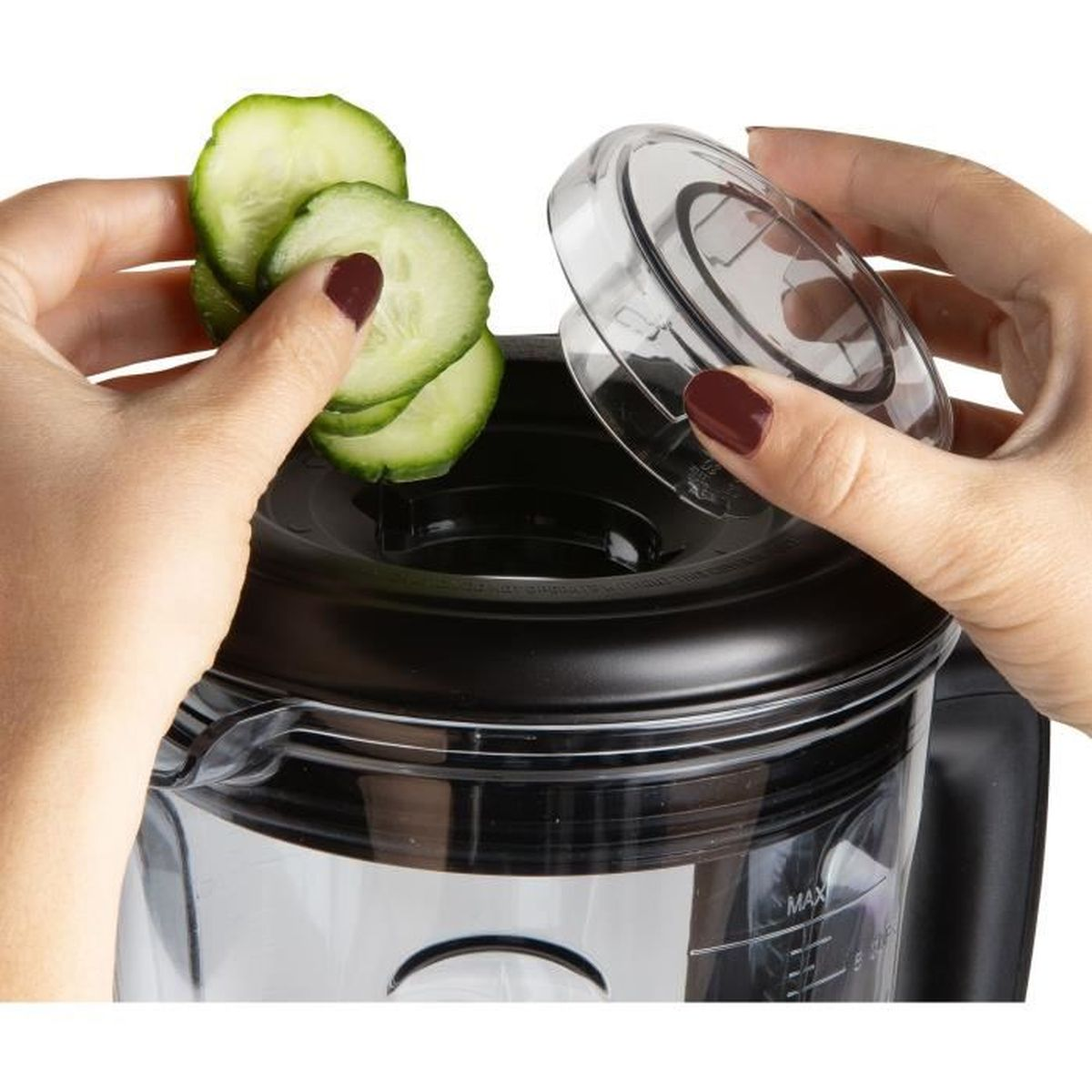 Mani che mettono fette di cetriolo in un frullatore con un coperchio trasparente accanto.
