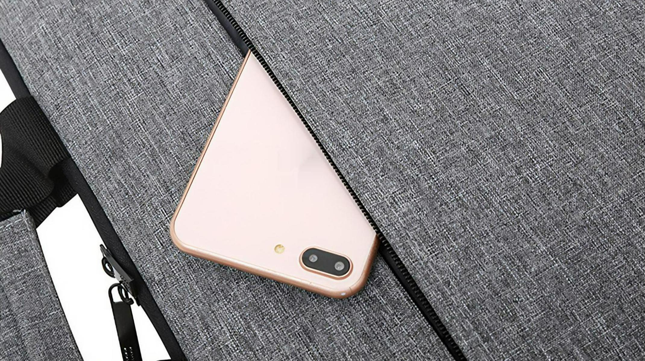 Nahaufnahme eines grauen Stoffes mit einem teilweise sichtbaren Telefon in einer Tasche.