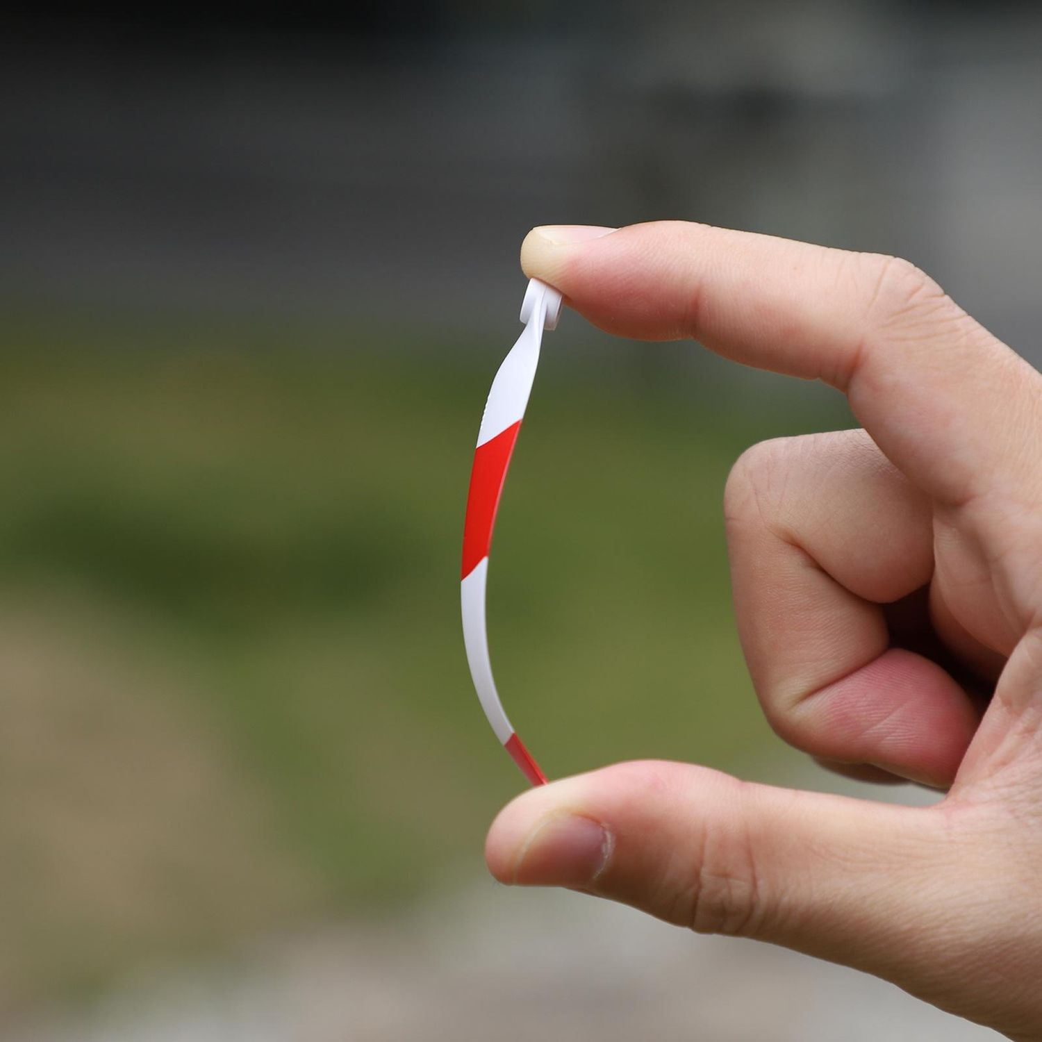 Una mano che tiene una piccola elica di drone con strisce rosse e bianche. L'elica è leggermente piegata.