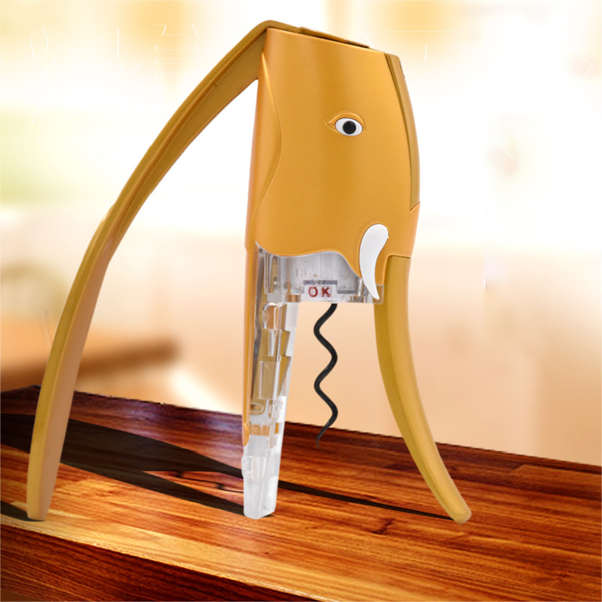 Ein elefantenförmiger goldener Weinöffner auf einem Holztisch. Weißer Hintergrund.