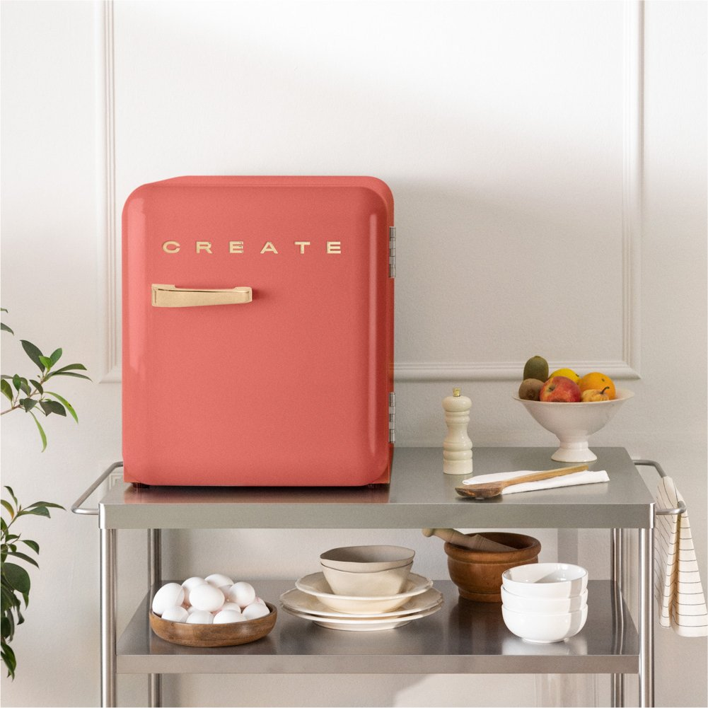 Un refrigerador coral con CREATE. Un cuenco de fruta, cuenco de huevos y otros artículos en un carrito.