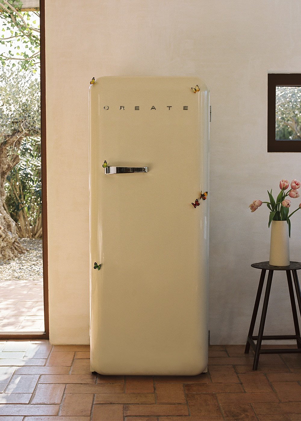 Un refrigerador crema con mariposas en una habitación. La palabra CREATE está en la puerta.