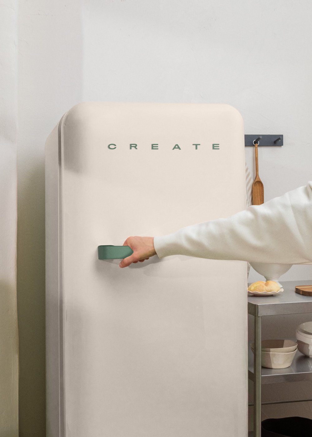 Refrigerador crema con manija verde. Mano alcanza la manija. CREATE en la puerta.