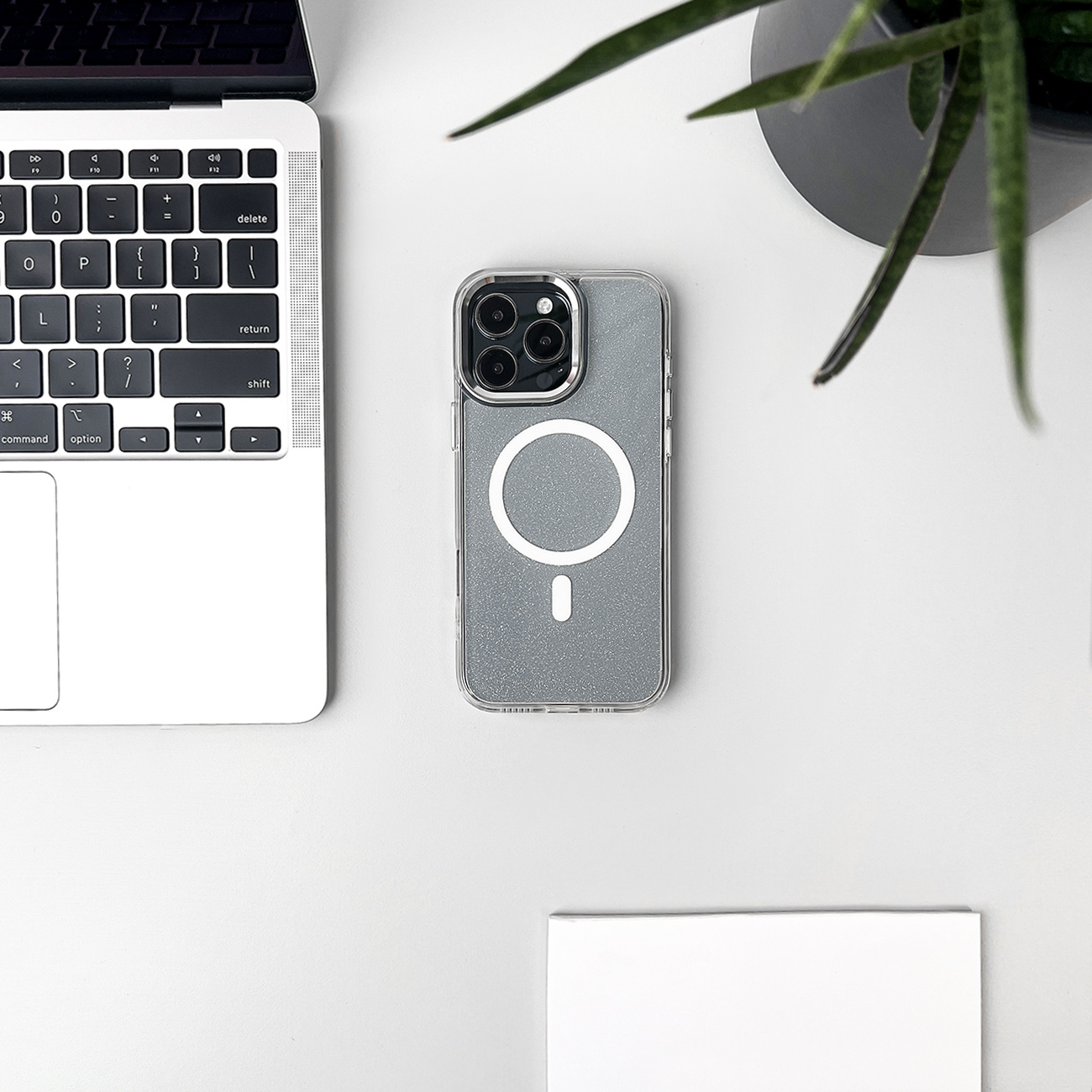 Etui na telefon z laptopem i rośliną na białym biurku, widok z góry, prezentujący design etui.