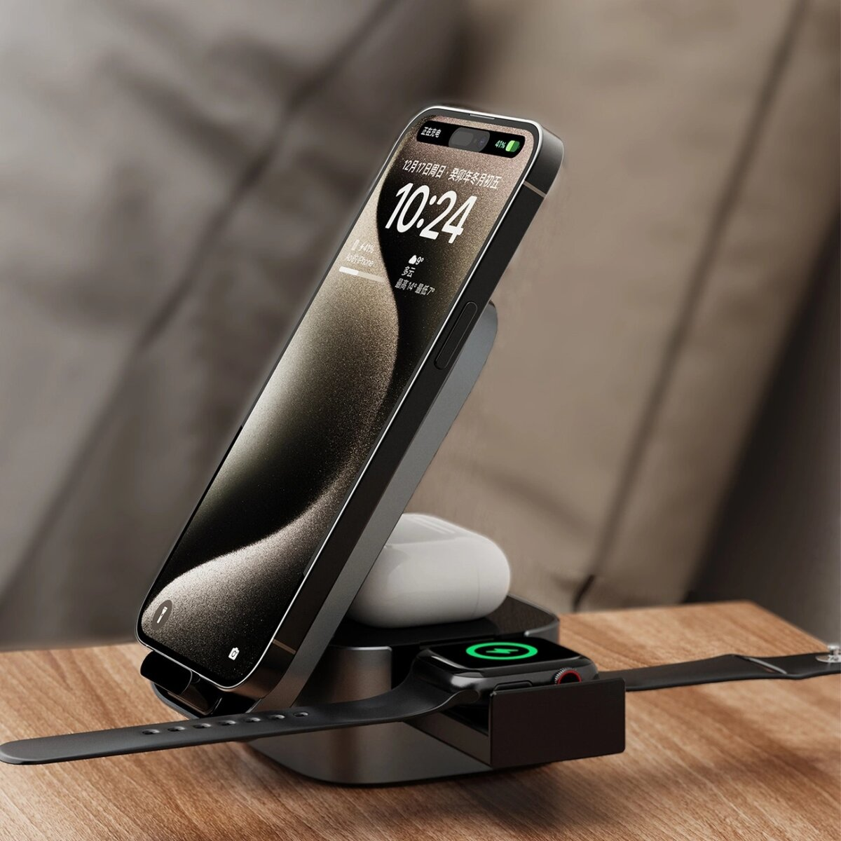 Telefon, AirPods i zegarek ładują się na czarnej stacji ładującej. Telefon wyświetla godzinę. Białe tło.