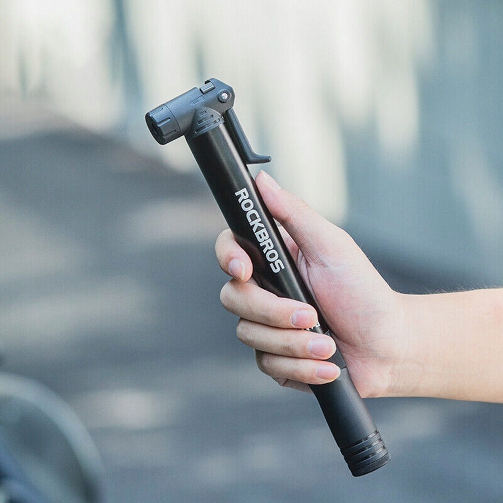 Czarna pompka rowerowa Rockbros trzymana przez dłoń, na białym tle.