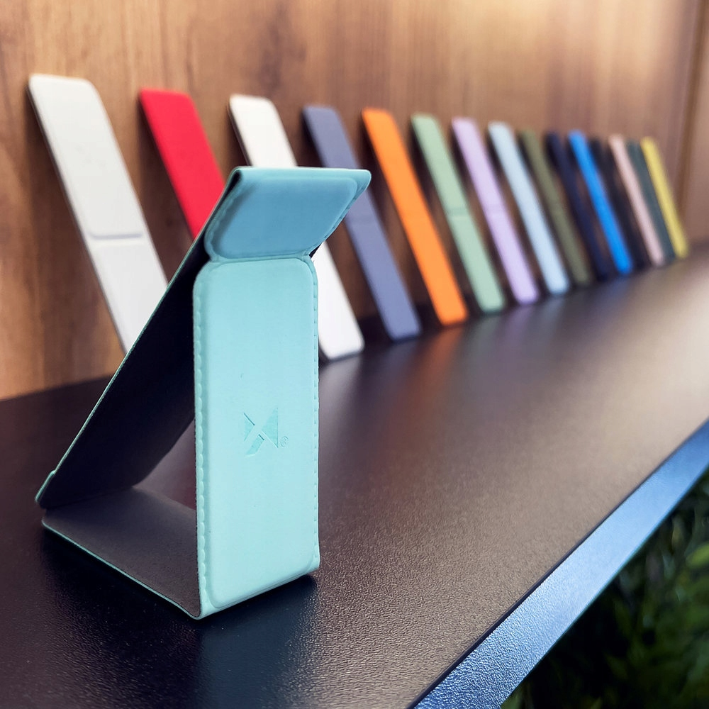 Wiele stojaków na telefony w różnych kolorach na czarnej powierzchni. Tło jest rozmyte.