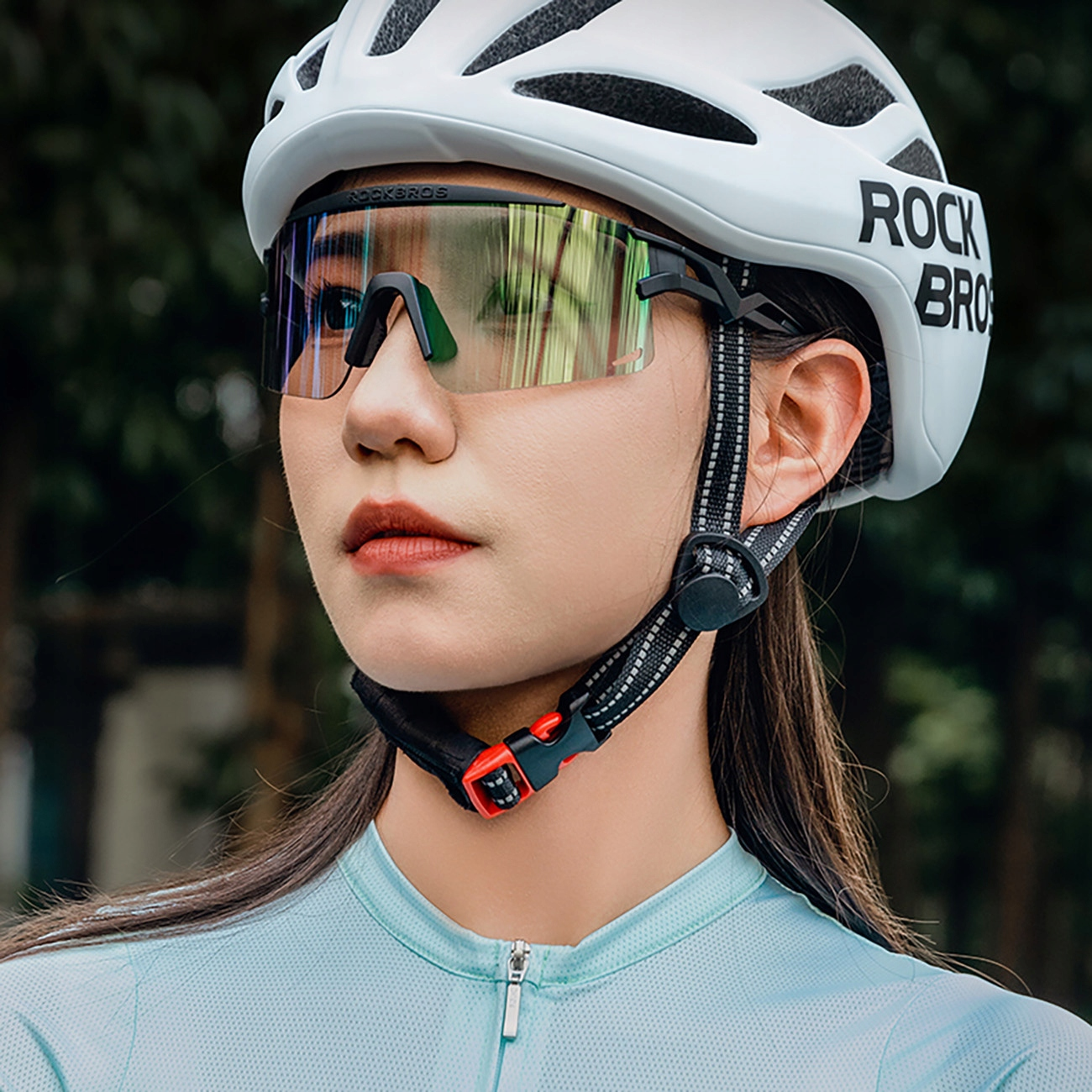 Eine Frau mit weißem Helm und Sportsonnenbrille, mit blauem Oberteil und schwarzem Riemen.