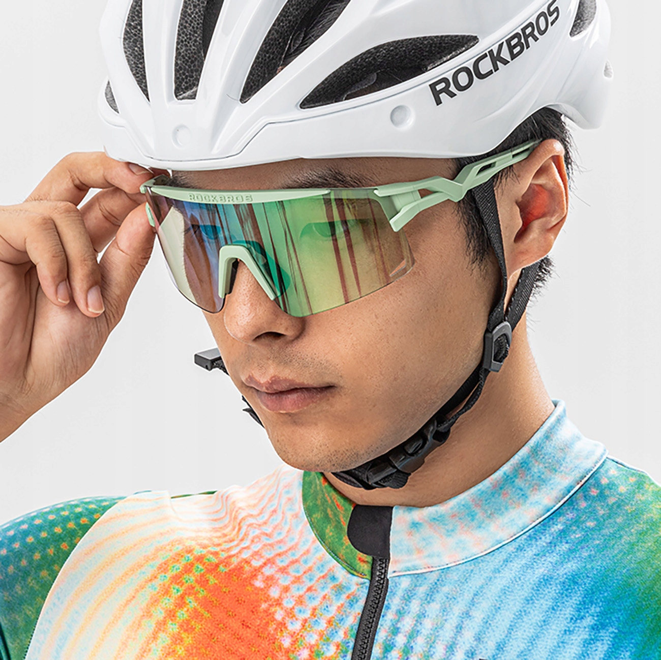 Nahaufnahme einer Person mit Radbrille. Brille ist grün und schwarz, Person trägt Helm.