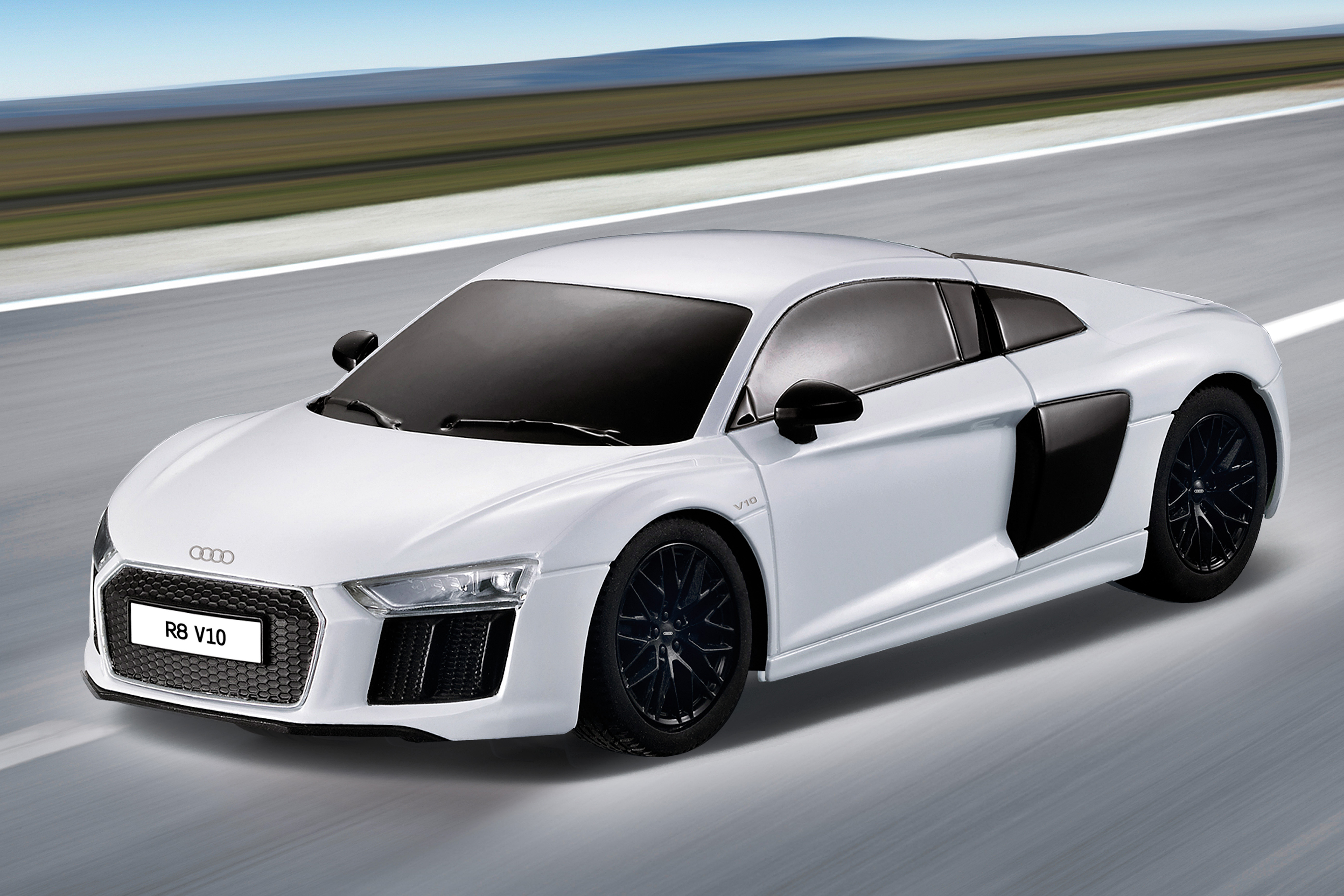 Weißes Audi R8 Spielzeugauto auf einer Straße. Mit schwarzen Rädern und R8 V10 Logo. Straße unscharf.